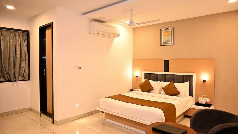 A stylish bedroom featuring a large bed with a green headboard and textured wall art - TGI Insignia, Bhopal