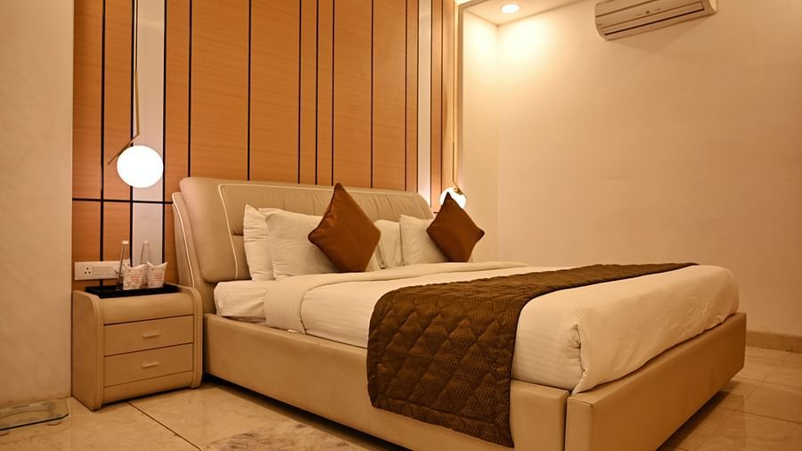 An elegant bedroom with a beige upholstered bed and a unique pendant light - TGI Insignia, Bhopal
