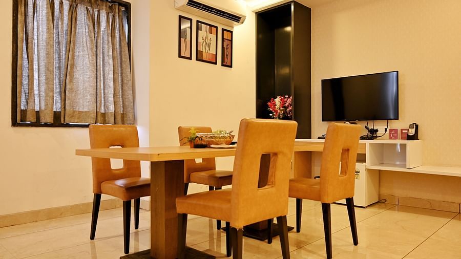 A dining room with a wooden table and chairs and a TV unit on the side - TGI Insignia, Bhopal
