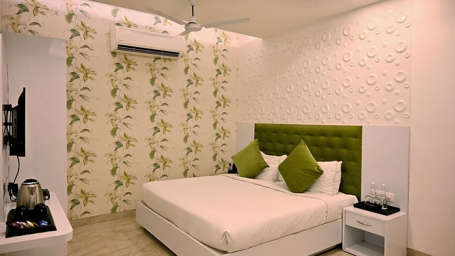 A chic bedroom with a patterned feature wall, modern decor and a green velvet headboard - TGI Insignia, Bhopal