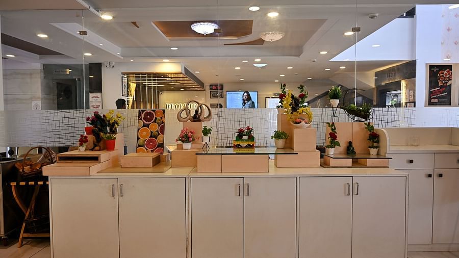 A bright and neatly organised juice bar counter decorated with fresh flowers and fruit displays - TGI Insignia, Bhopal