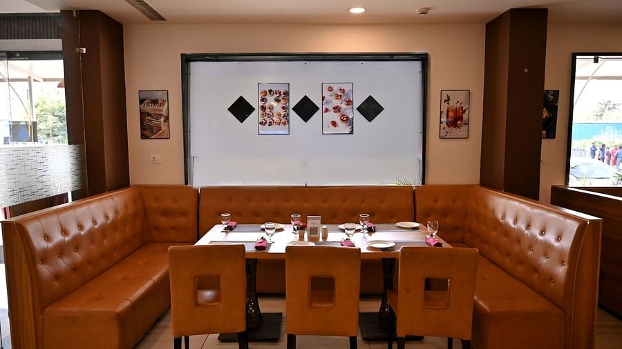 Cosy dining corner with a brown leather booth and wooden tables in a restaurant - TGI Insignia, Bhopal