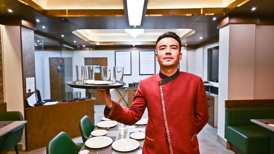 The waiter elegantly holding the dishes, prepared to serve, at The Soma Hotel by Avianna Group, Darjeeling