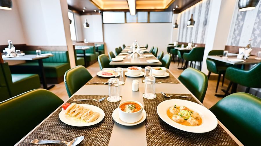 A spacious restaurant with wooden tables and chairs, featuring a variety of dishes set on the tables at The Soma Hotel by Avianna Group, Darjeeling