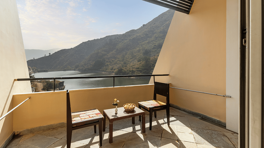 A balcony view with neatly arranged table and chairs under a sunny day - Via Lakhela Resort & Spa