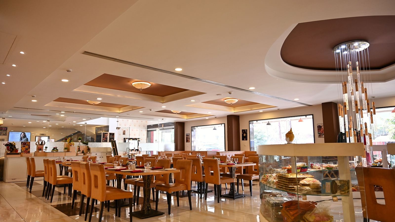 Hotel dining area with neatly arranged tables, contemporary art and a service counter - TGI Insignia, Bhopal