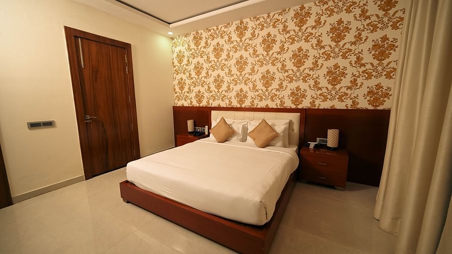 A room consisting of a clean bed, a side drawer and curtains - Clarks Safari, Ranthambore