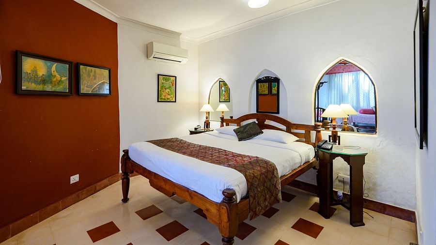 Hill Fort Kesroli 14th Century Alwar - interior view of the Naruka Burj - Countryside View room with a queen size bed, burgundy-coloured wall and lamps on either side 