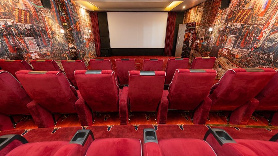 Rows of plush red seats in an ornately decorated cinema with walls draped in patterned rugs