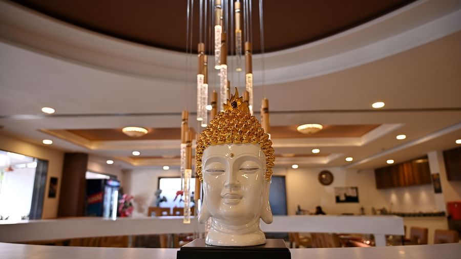 Close-up of a Buddha statue with a golden headpiece in a hotel lobby - TGI Insignia, Bhopal