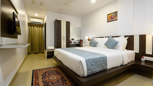 Side view of Deluxe Room featuring a cozy bed and a TV mounted on the wall at Biznotel by Pride, Deoghar.