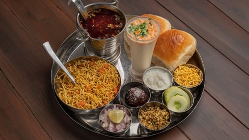 A traditional Indian thali with assorted dishes including rice, dal, vegetables, chutneys, salad, and bread served on a large metal plate.