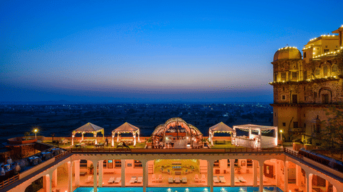 An elevated view of a rectangular pool with tented structures alongside a building at Tijara Fort-Palace - 19th Century, Alwar.
