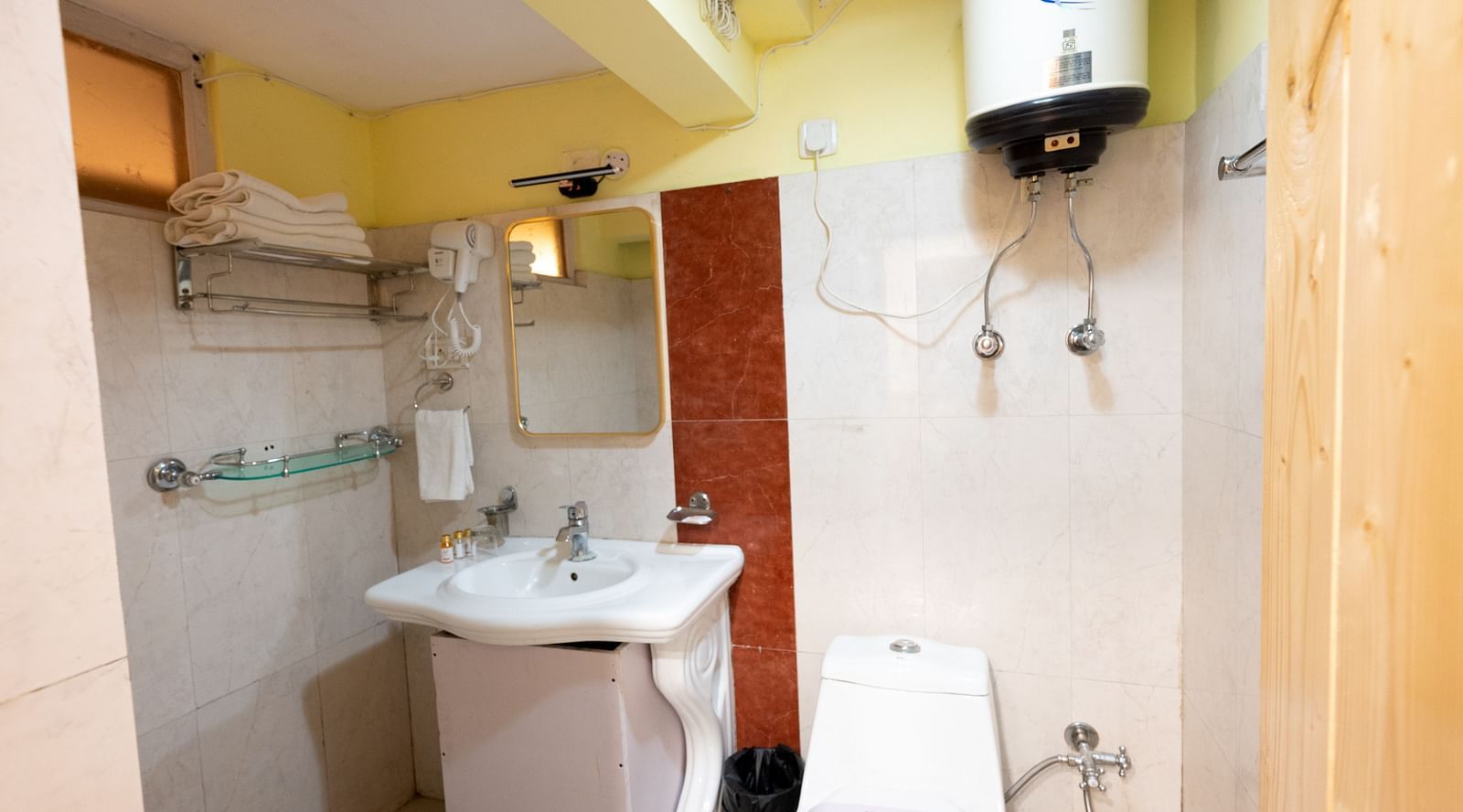 Deluxe rooms bathroom equipped with a washbasin, mirror, geyser, and western toilet2
