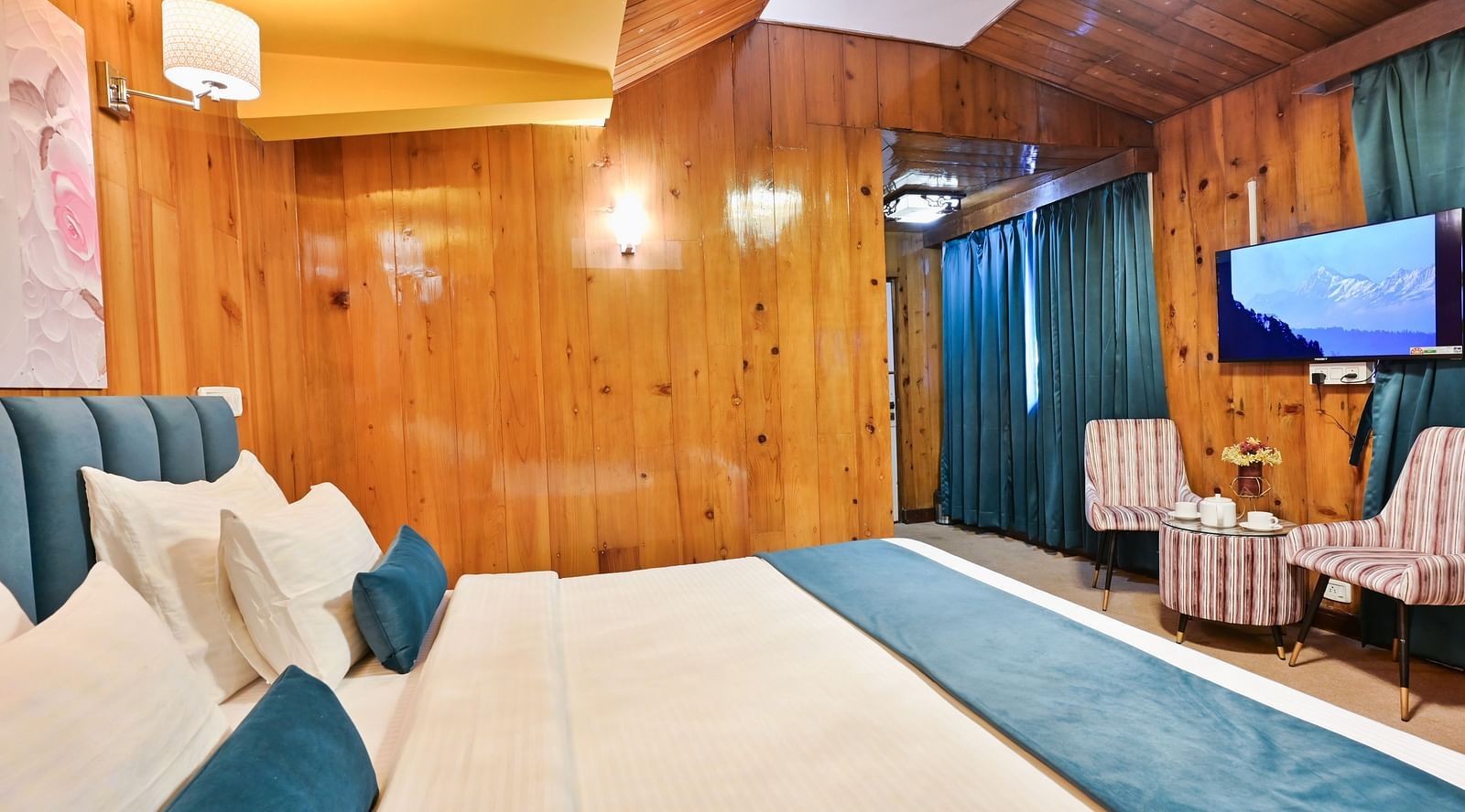 Premium room featuring a king sized bed, wall mounted television, windows with curtains, and warm lighting at Avianna Seven Seas, Darjeeling12