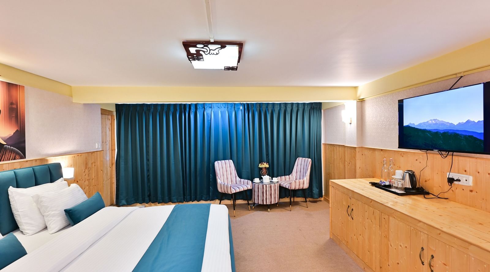 Premium room featuring a king sized bed, wall mounted television, windows with curtains, and warm lighting at Avianna Seven Seas, Darjeeling15