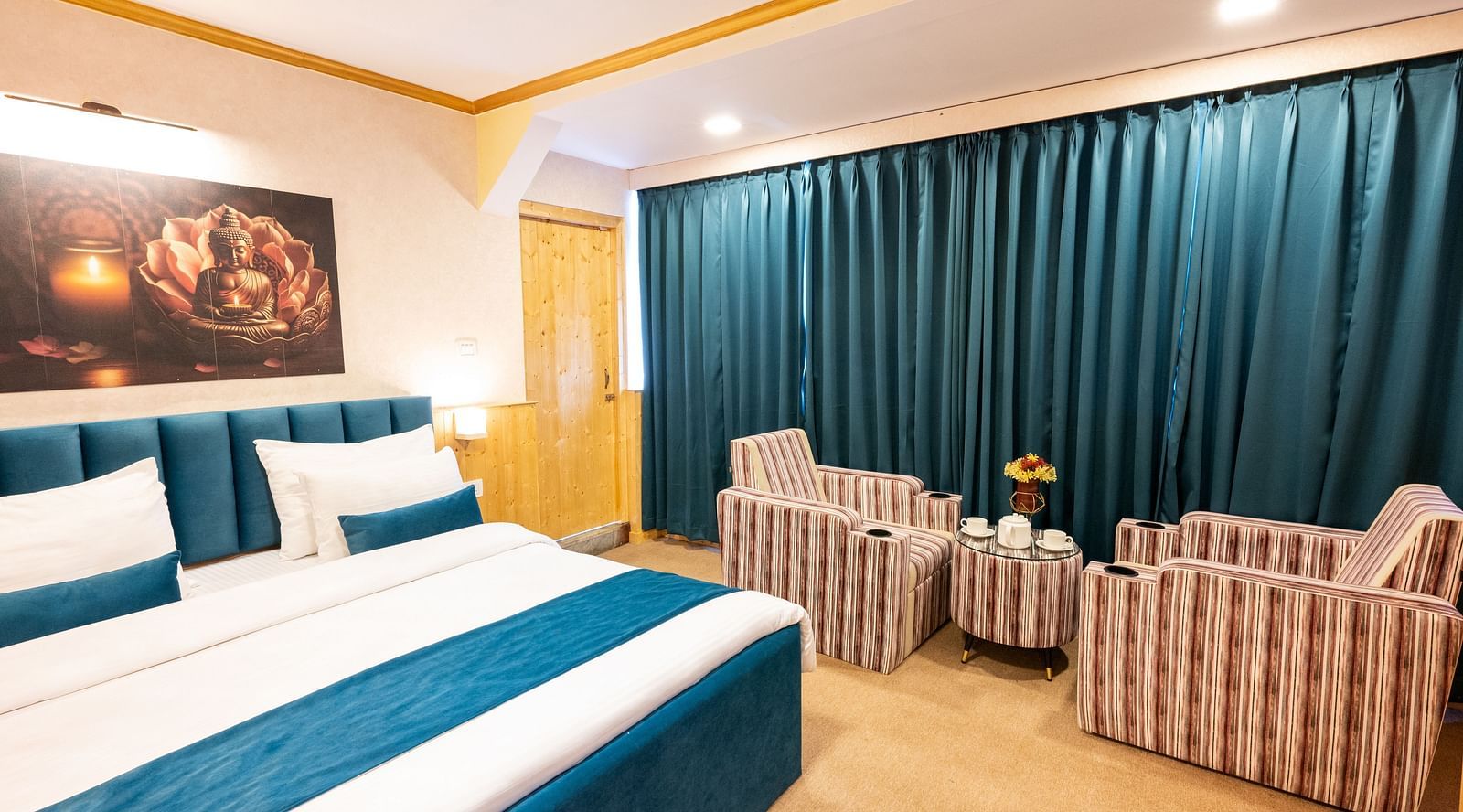 The suite features a spacious bed, large windows stretching along one side of the room, comfortable cushioned furniture, and warm lighting at Avianna Seven Seas, Darjeeling2
