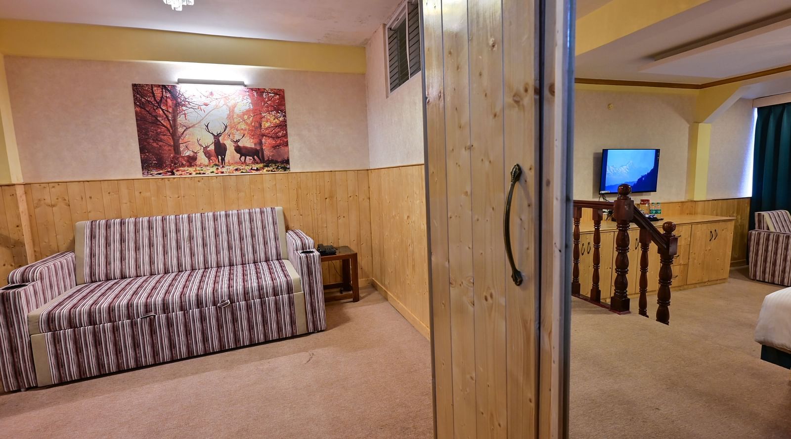 The suite features a spacious bed, large windows stretching along one side of the room, comfortable cushioned furniture, and warm lighting at Avianna Seven Seas, Darjeeling9