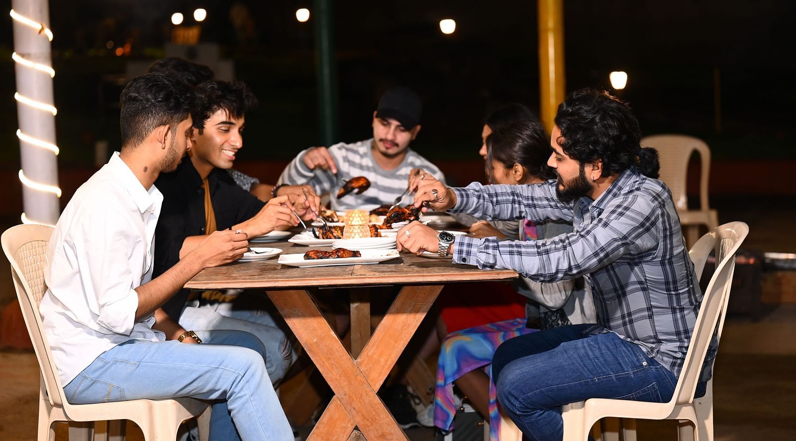 our young adults engaged in playing a board game at an outdoor setting during night | Diamond Parks, Pune