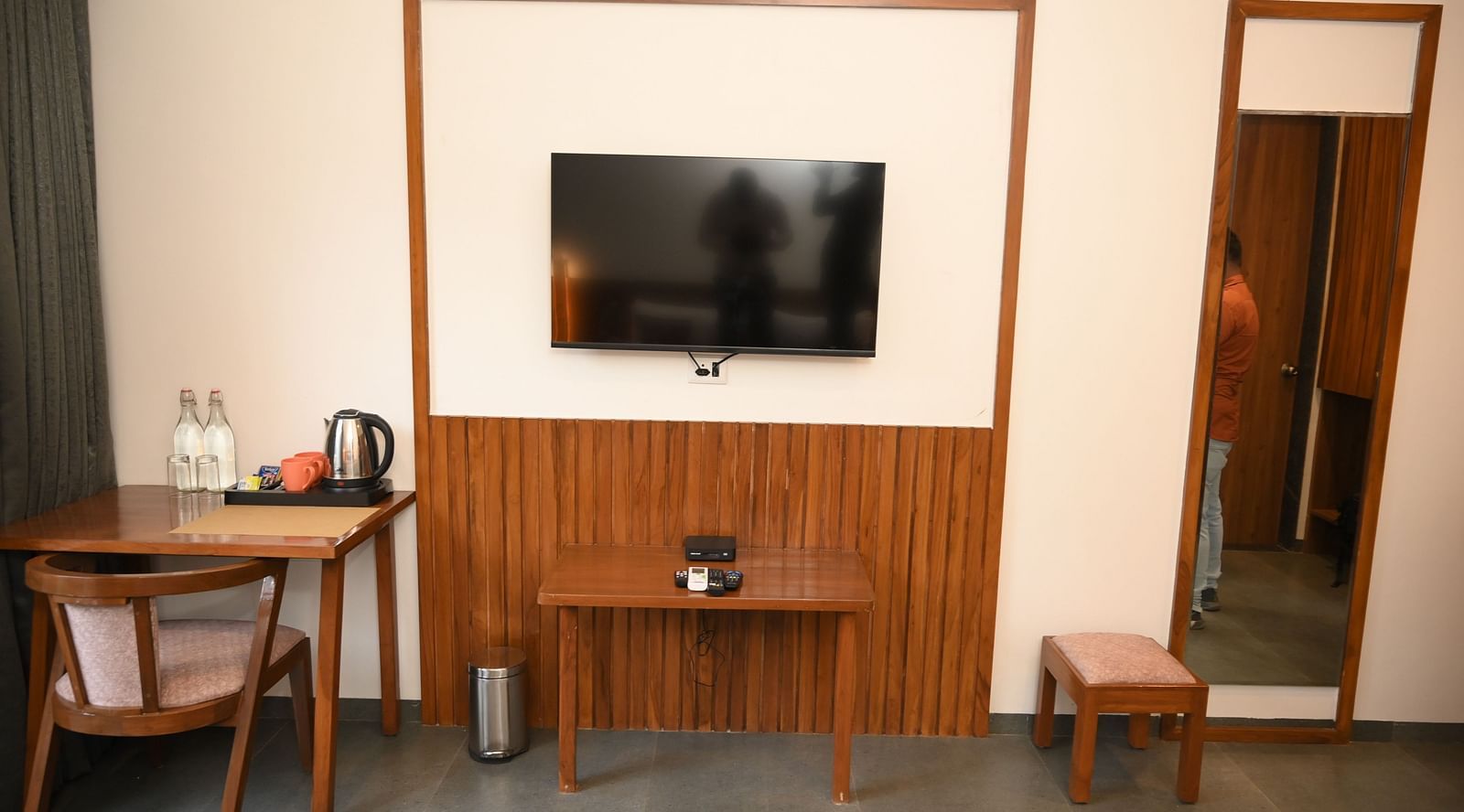 A television a table and a chair and a mirror at the Deluxe Cottage at Mango Leaf Lake Resort, Pune