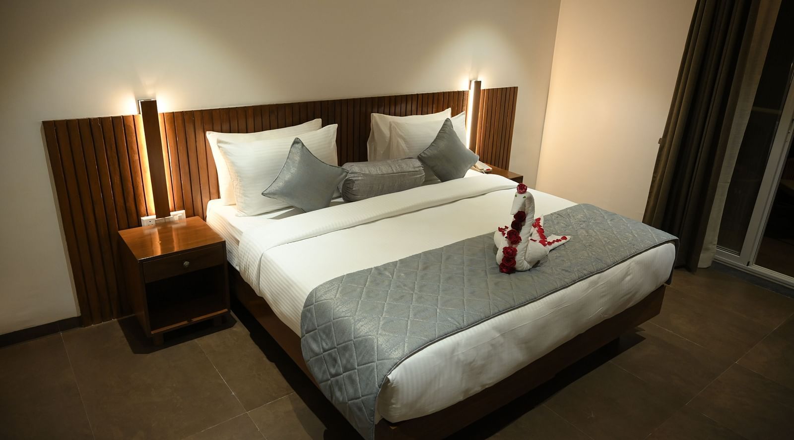 A doubled bed with a decorated towel at Deluxe room at  Mango Leaf Lake Resort, Pune