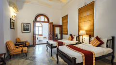 An overview of the Maharaja Yadavindra Singh room with a twin double bed, sofas on the side and entrance to the bathroom - The Baradari palace