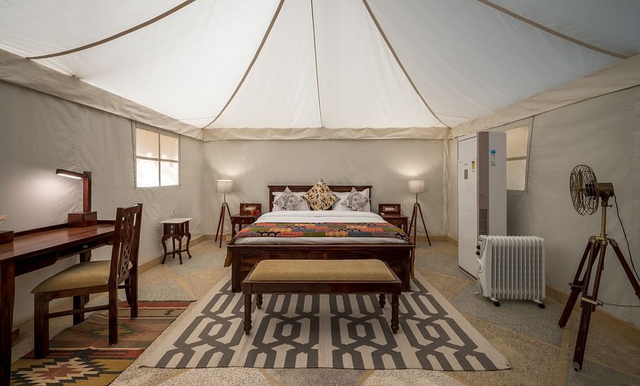 alt-text The interiors of the accommodations contain a spacious bed, work desk and other amenities - Karwaan Jaisalmer
