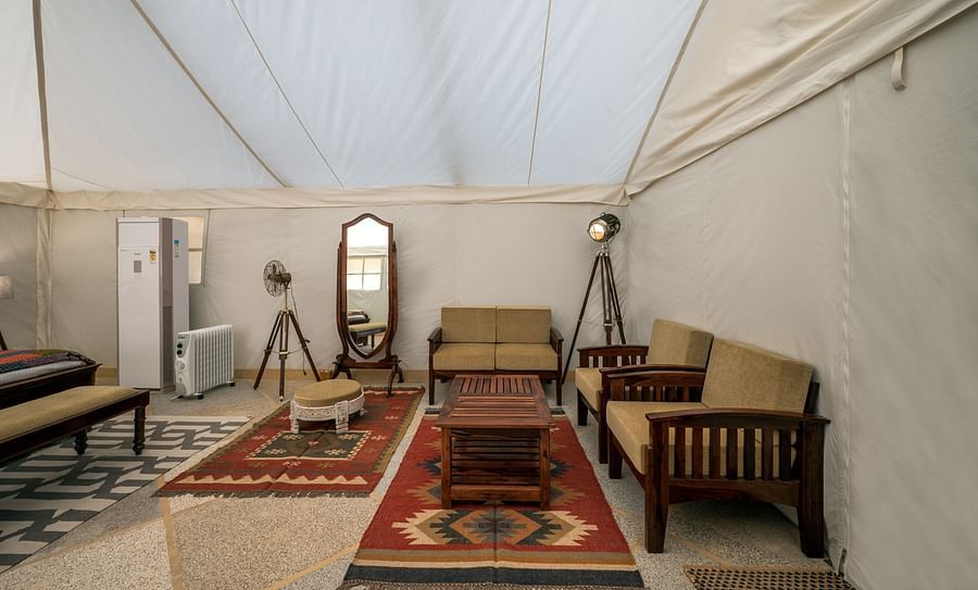 alt-text The interiors of the accommodations contain sofas, a teapoy and a mirror - Karwaan Jaisalmer