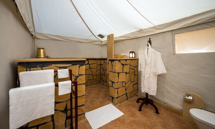 alt-text The bathrobe and towels are hung on the clothes stand in the washroom - Karwaan Jaisalmer