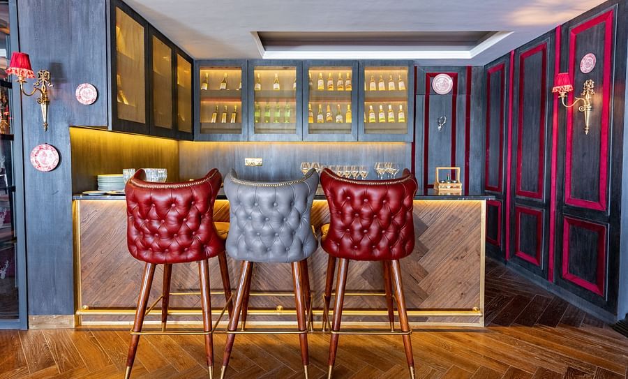 alt-text Two red coloured high chairs place in front of a bar counter - The Manor Luxury Hotel, Shimla