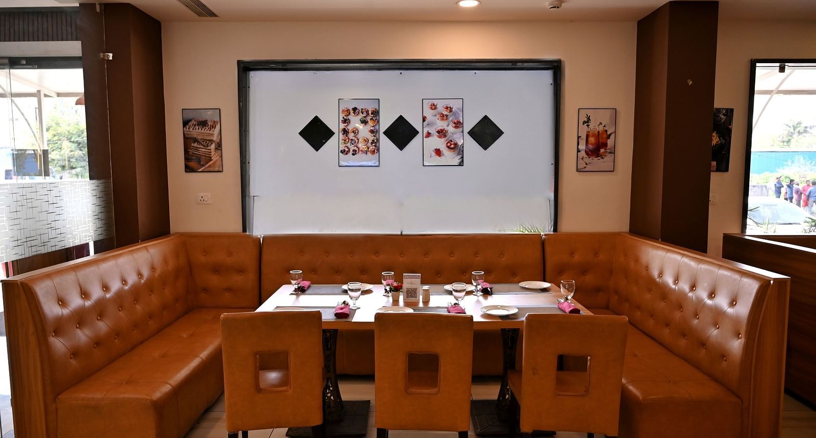 Cosy dining corner with a brown leather booth and wooden tables in a restaurant - TGI Insignia, Bhopal