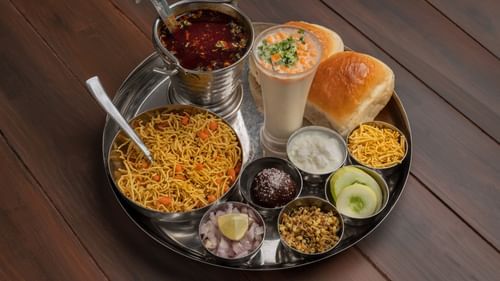 A traditional Indian thali with assorted dishes including rice, dal, vegetables, chutneys, salad, and bread served on a large metal plate.
