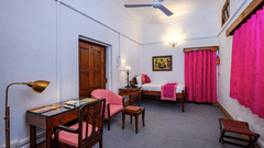 An overview of the Bibi Rajkumari Sahib Kaur room with a double bed, study table and chairs - The Baradari palace