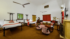 An overview of the Maharaja Narinder Singh room with twin double bed, chairs, coffee table in front of the tv - The Baradari palace