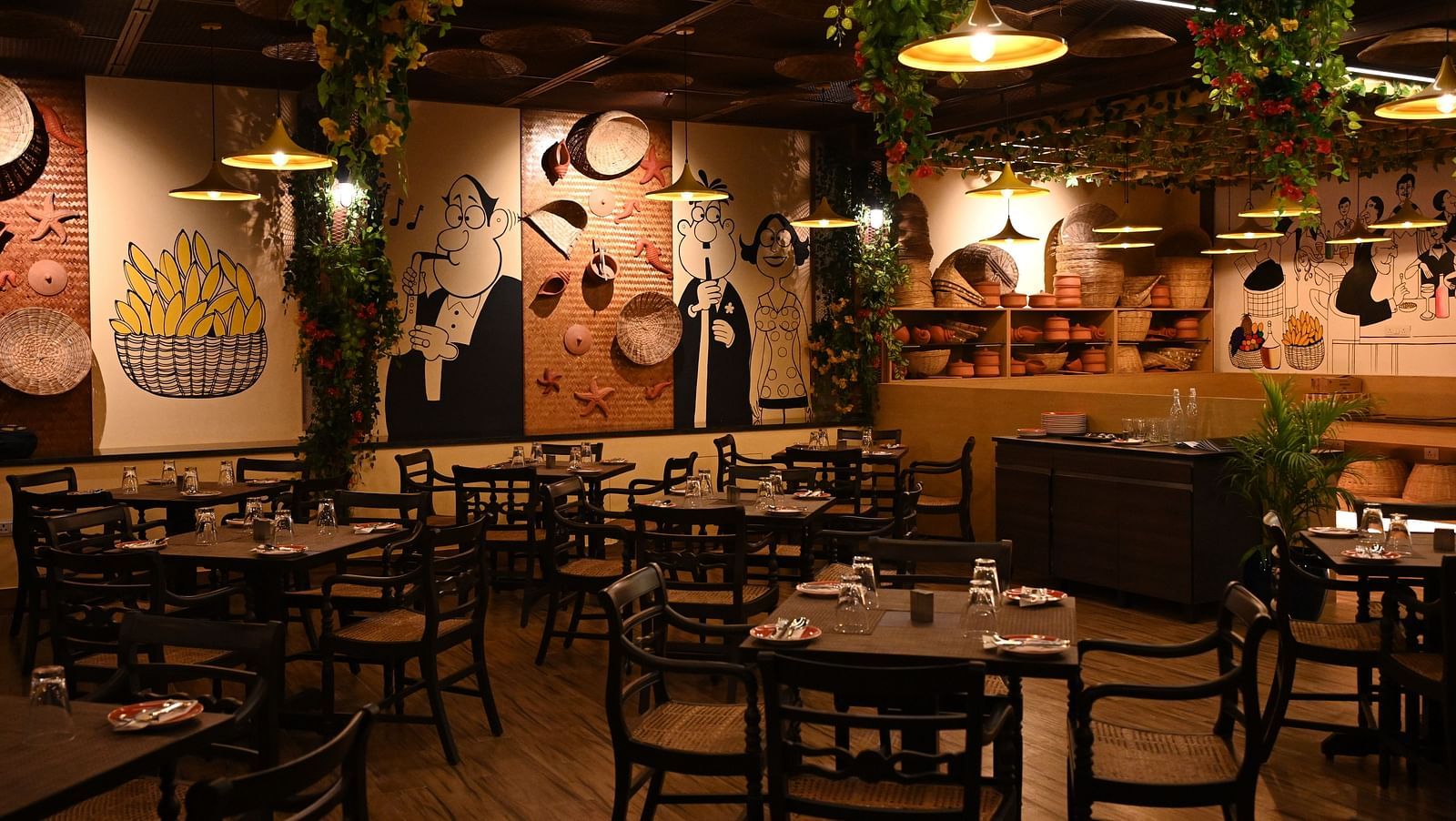 An image of a cafe with several sets of tables and chairs and the walls are  painted with doodles - Essentia Premier Hotel, Chennai.