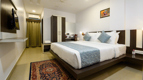Side view of Deluxe Room featuring a cozy bed and a TV mounted on the wall at Biznotel by Pride, Deoghar.