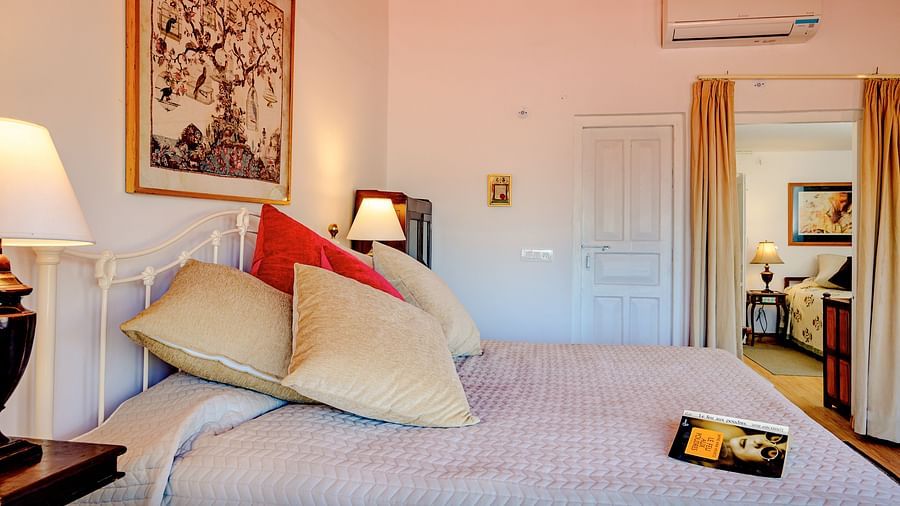 Side view of room with bed, cushions and table lamp inside Rose room at The Ramgarh Bungalows - 19th Century, Above Nainital.