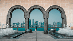 A view of a lady looking at the city line through an arched gateway