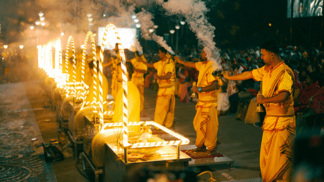Priests performing a vibrant Ganga Aarti ceremony at night.