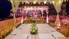 A long table set with cutlery and flowers under a tented structure, with chairs, at Tijara Fort-Palace - 19th Century, Alwar.