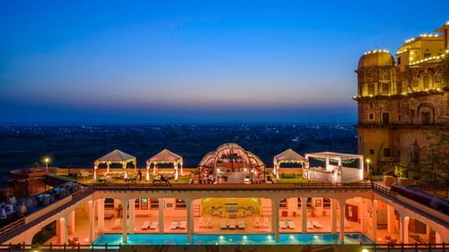 An elevated view of a rectangular pool with tented structures alongside a building at Tijara Fort-Palace - 19th Century, Alwar.