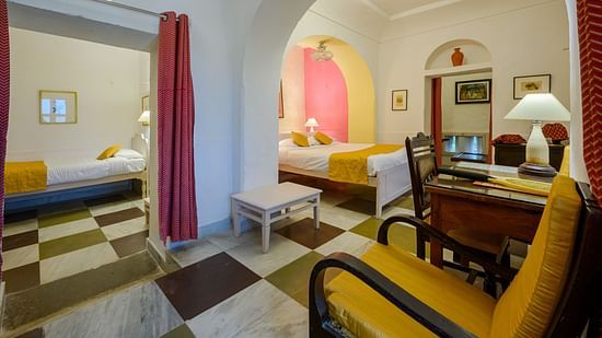 Hill Fort Kesroli 14th Century Alwar - interior view of the Raunak Mahal - Village View room featuring checkered floor, queen size bed, a chair and red curtains 