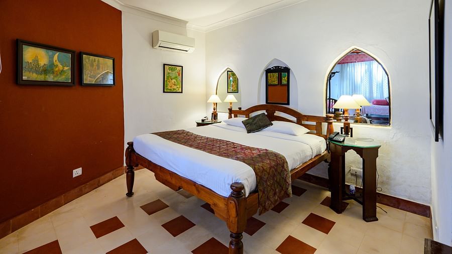 Hill Fort Kesroli 14th Century Alwar - interior view of the Naruka Burj - Countryside View room with a queen size bed, burgundy-coloured wall and lamps on either side 