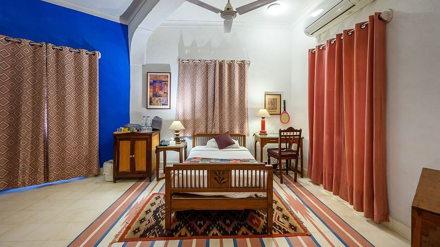 Hill Fort-Kesroli 14th Century Alwar - Interior view of the Sultan Mahal - Countryside View room with beige and red curtains, single bed and a ceiling fan