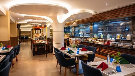 A dining space with tables and chairs at Grand Kakinada by GRT Hotels — a famous restaurant in Kakinada.