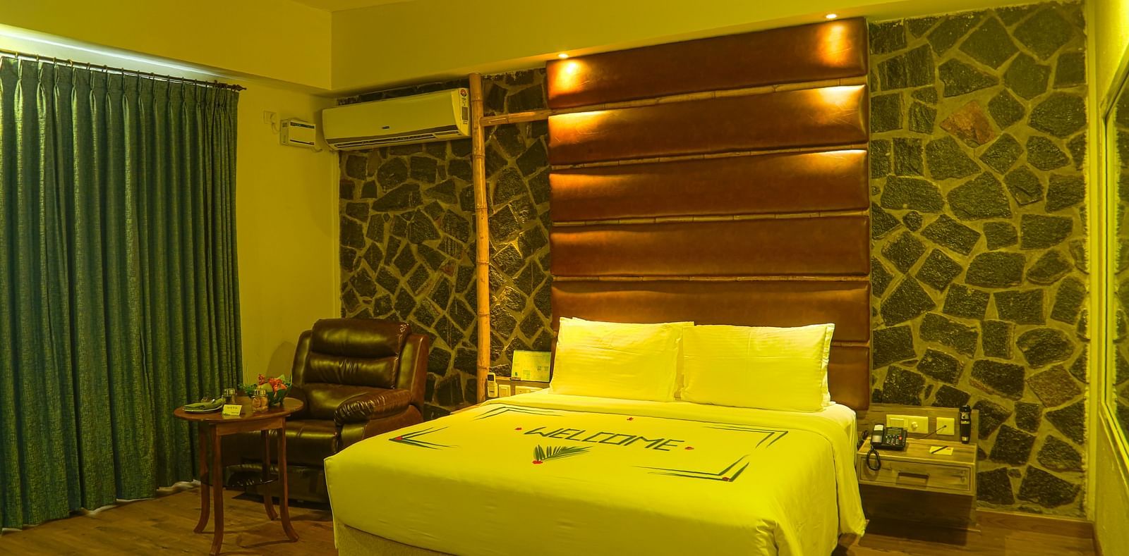An image of a trail view room with a king size bed, bed side table, a chair, a table with bright lighting - Great Trails Yercaud by GRT Hotels
