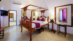 An overview of the Rani Fateh Kaur room with a double bed, mirror, and side tables - The Baradari palace
