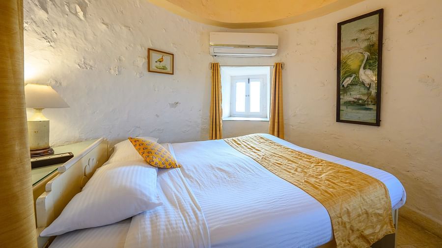 Hill Fort Kesroli 14th Century Alwar - interior view of the Saras Mahal featuring a queen size bed, white walls and yellow-coloured ceiling