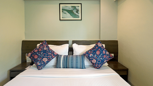Executive room with a large bed, spreads, pillows, and wall-art at Le Grande Mumbai.