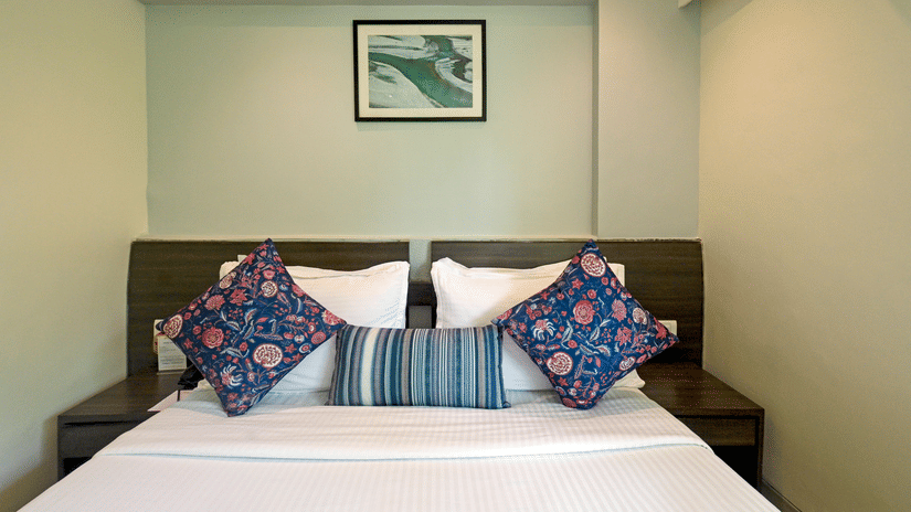 Executive room with a large bed, spreads, pillows, and wall-art at Le Grande Mumbai.